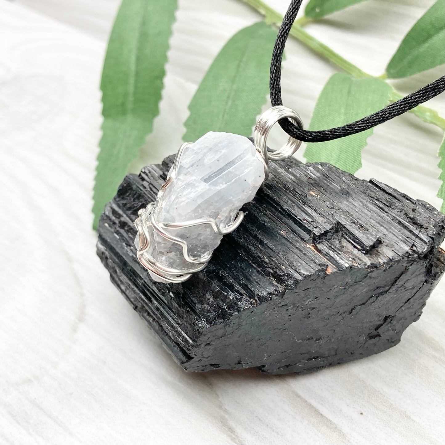 Natural Blue Calcite Necklace. Blue Calcite crystal wrapped with tarnish resistant silver colored copper wire. Pendant comes on a black lobster claw necklace with silver ends.