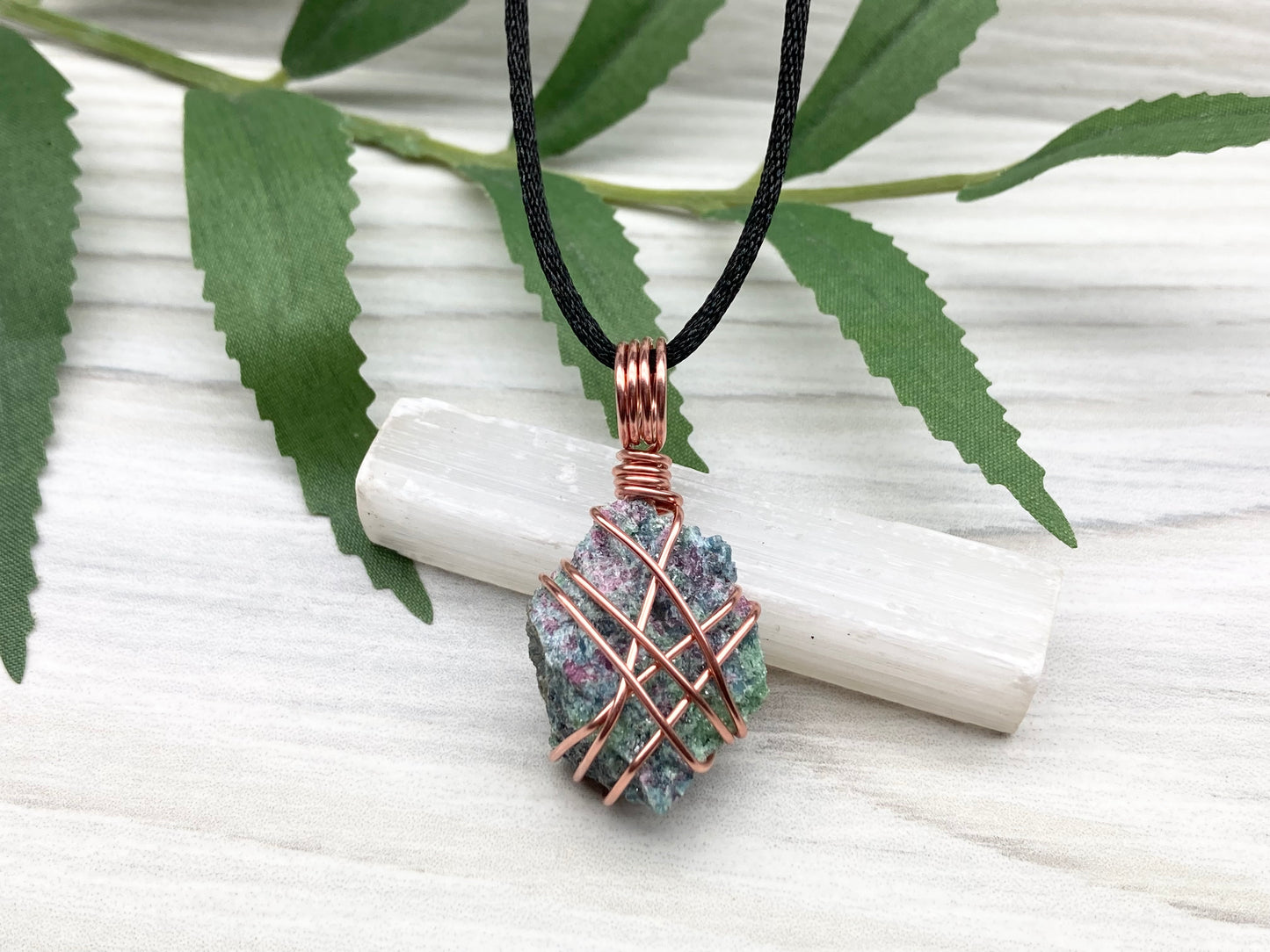 Raw Ruby Zoisite Necklace. This Ruby Zoisite Crystal Is Hand Wrapped With Pure Copper Wire For A Pendant. This Stone is Blue, Red And Green Colored. Comes On A Black Chain. Spiritual New Age Style Jewelry.