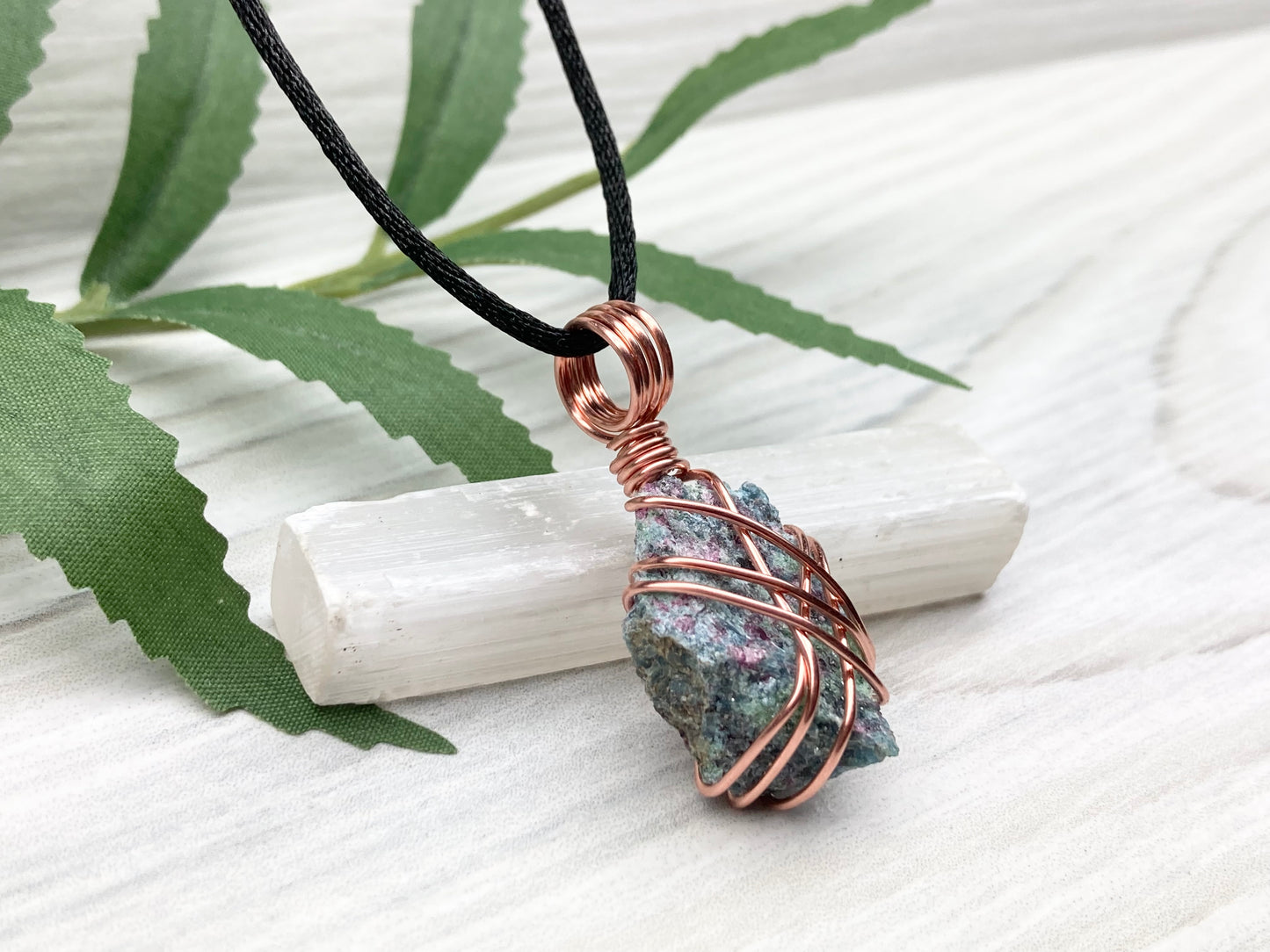 Raw Ruby Zoisite Necklace. This Ruby Zoisite Crystal Is Hand Wrapped With Pure Copper Wire For A Pendant. This Stone is Blue, Red And Green Colored. Comes On A Black Chain. Spiritual New Age Style Jewelry. Right Side View.