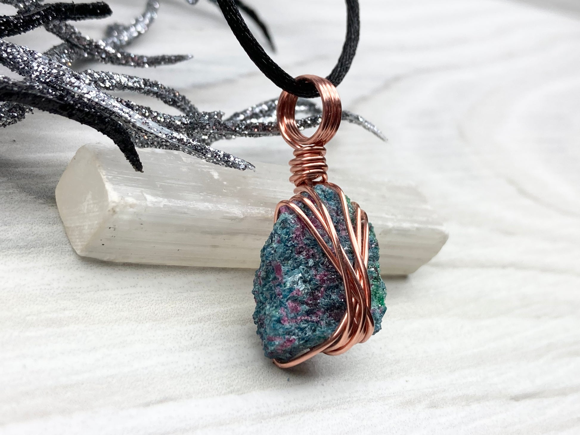 Real Raw Ruby Zoisite Necklace. Right Side View. This Ruby Zoisite Crystal Is Hand Wrapped With Pure Copper Wire. This Stone is Blue, Green and Red Colored. Gemstone Comes On A Black Chain. Boho Spiritual Style Unisex Jewelry.