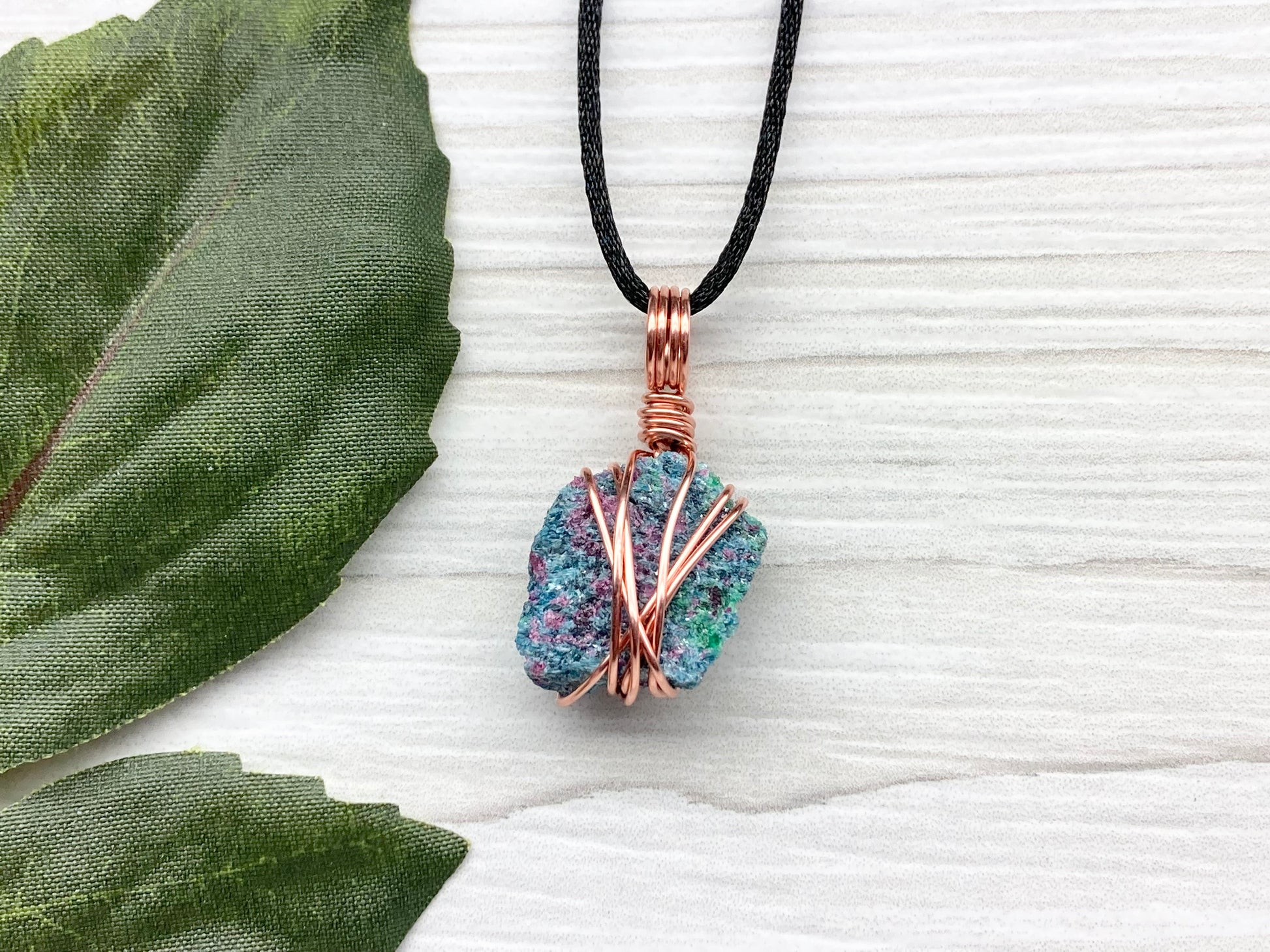 Real Raw Ruby Zoisite Necklace. This Ruby Zoisite Crystal Is Hand Wrapped With Pure Copper Wire. This Stone is Blue, Green and Red Colored. Gemstone Comes On A Black Chain. Boho Spiritual Style Unisex Jewelry.