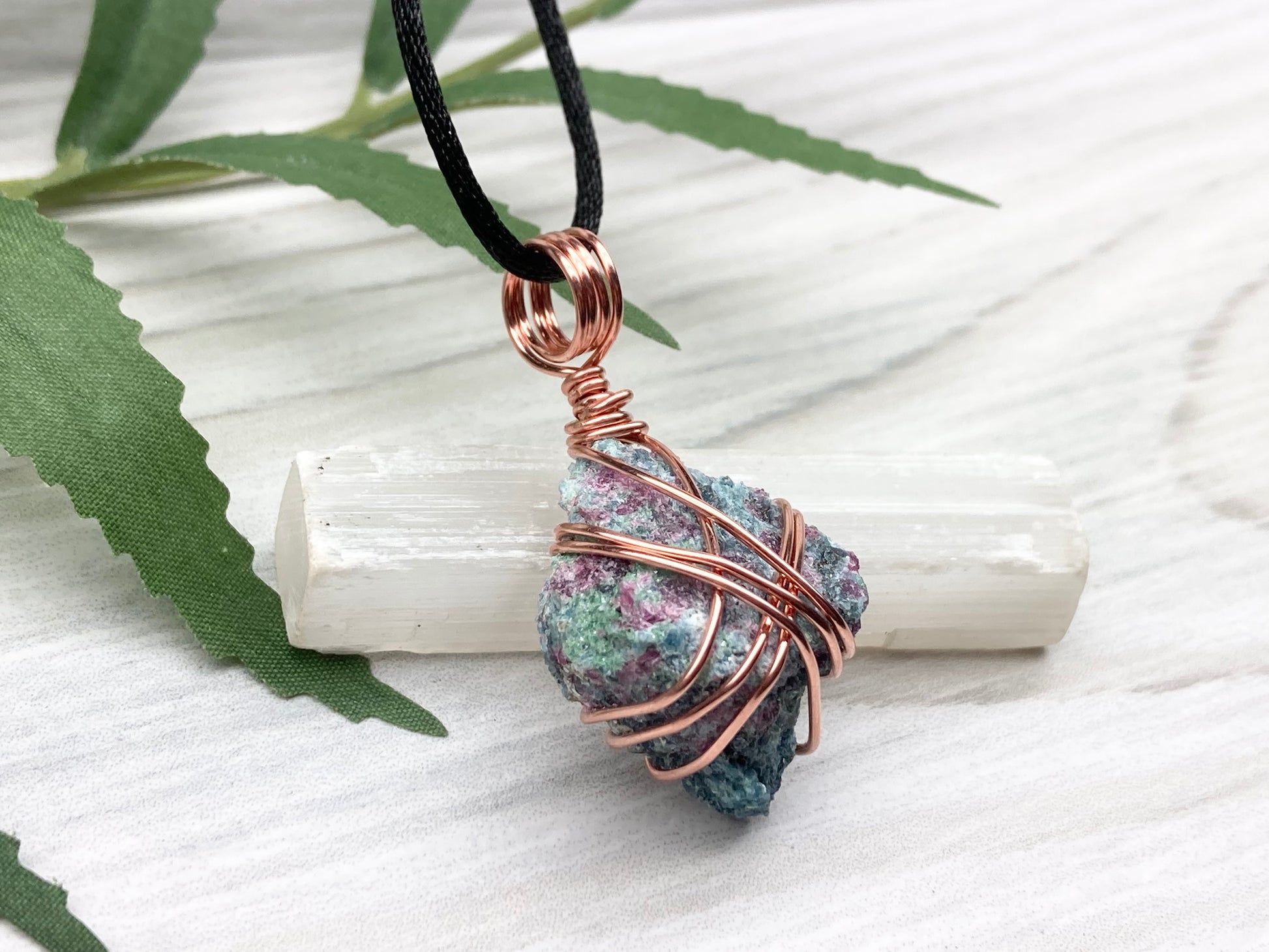 Rough Raw Ruby Zoisite Necklace. Right Side View. This Ruby Zoisite Crystal Is Hand Wrapped With Pure Copper Wire. This Stone is Blue and Red Colored. Gemstone Comes On A Black Chain. Spiritual New Age Style Unisex Jewelry.