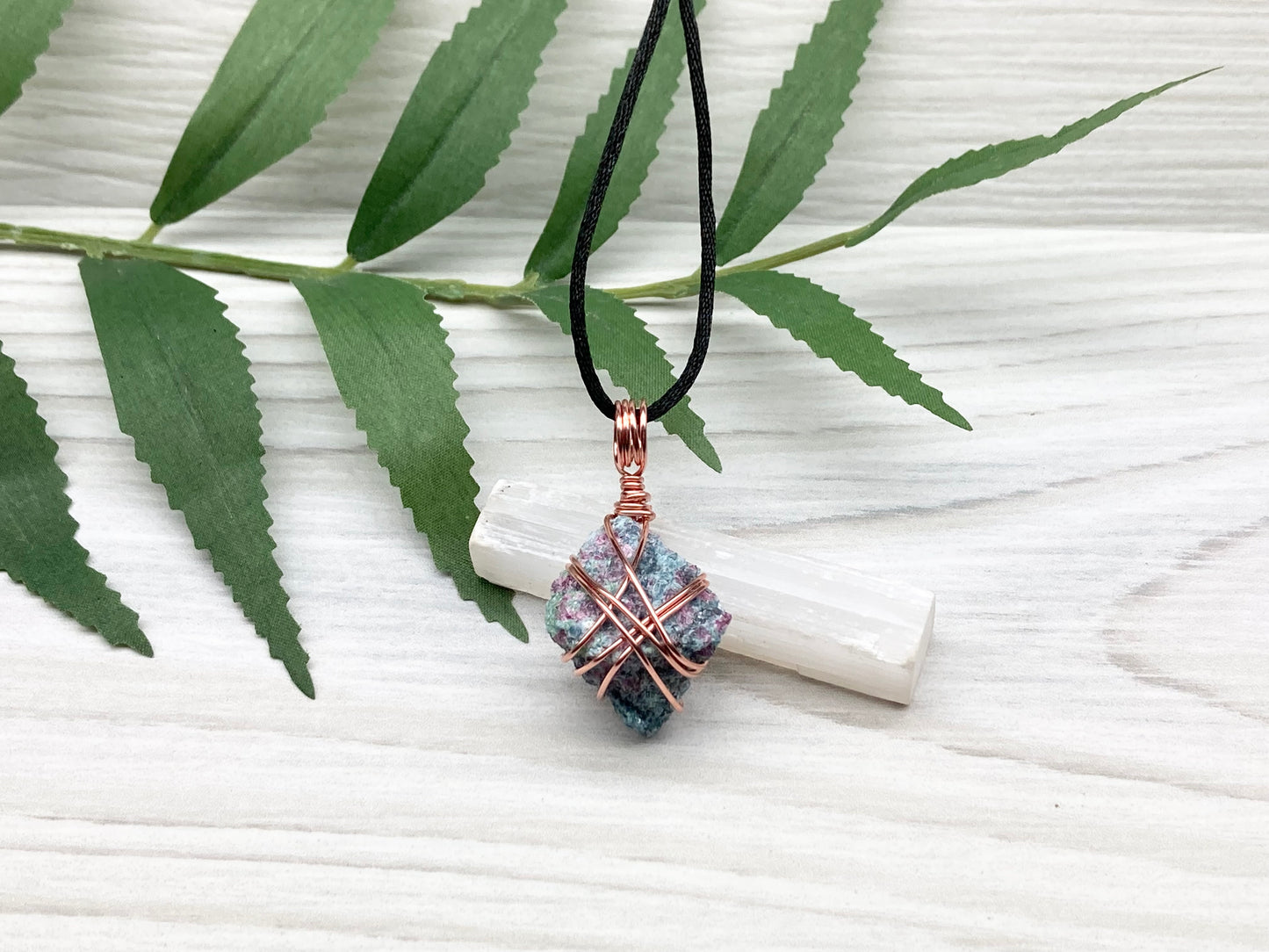 Rough Raw Ruby Zoisite Necklace. This Ruby Zoisite Crystal Is Hand Wrapped With Pure Copper Wire. This Stone is Blue and Red Colored. Gemstone Comes On A Black Chain. Spiritual New Age Style Unisex Jewelry.