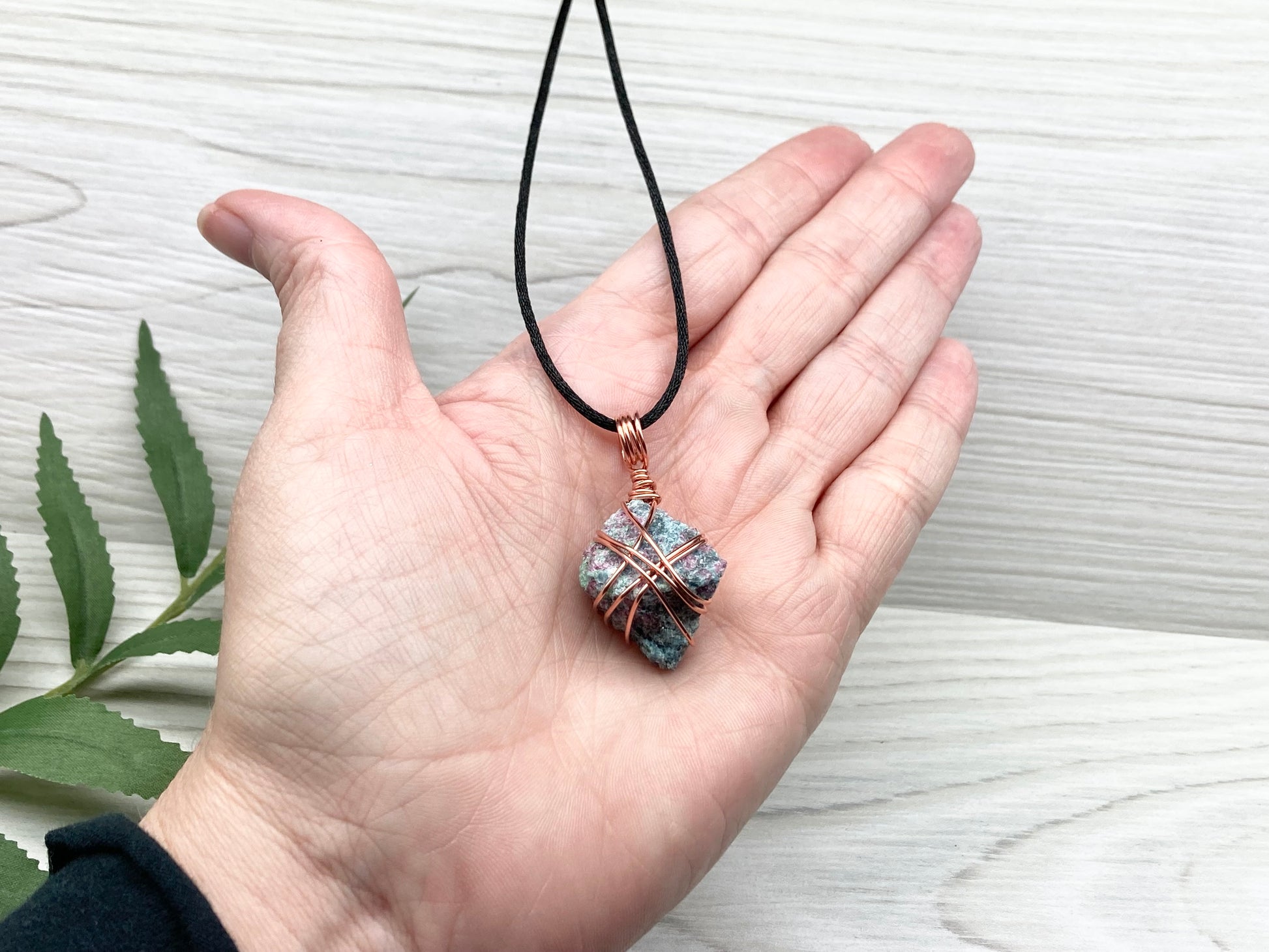 Rough Raw Ruby Zoisite Necklace. This Ruby Zoisite Crystal Is Hand Wrapped With Pure Copper Wire. This Stone is Blue and Red Colored. Gemstone Comes On A Black Chain. Pendant Measures 1.6 X 0.8 Inches. Spiritual New Age Style Unisex Jewelry.